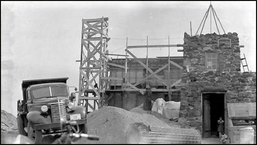 Construction of second (present) lookout on Mount Washburn, August 25, 1939.  Note first (stone) lookout building still standing in foreground.