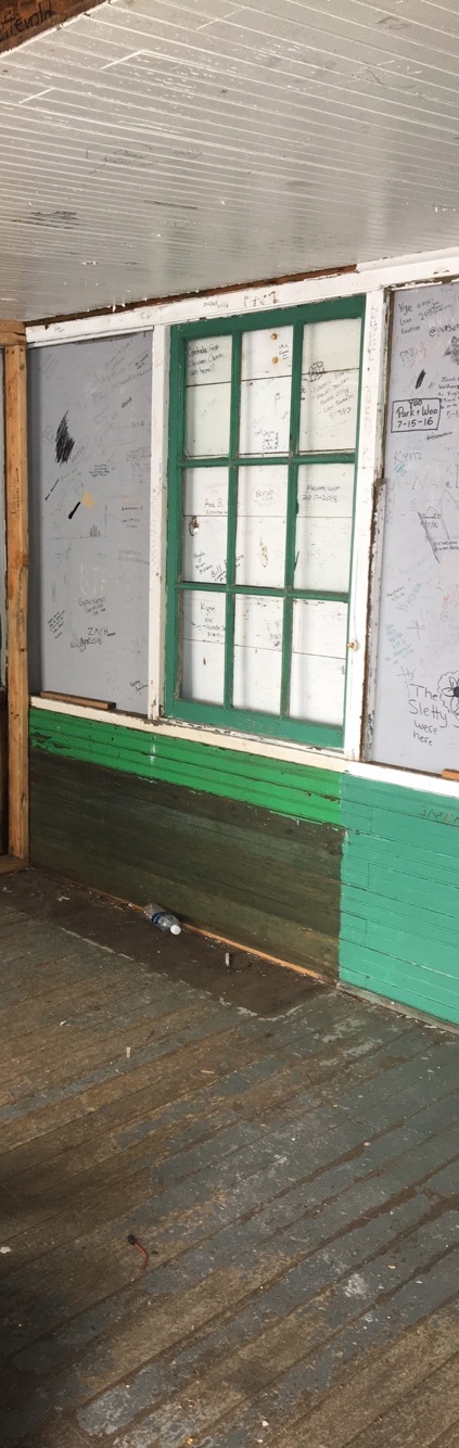 Cabin exterior with broken windows and graffiti